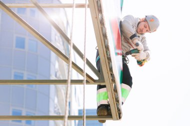 Miğferli ve boyuyla çalışan endüstriyel tırmanışçı. Riskli bir iş. Profesyonel işçi.