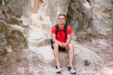 Sırt çantalı genç erkek yürüyüşçü dinleniyor. Aktif sağlıklı yaşam tarzı macera seyahatleri