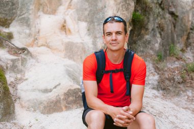 Sırt çantalı genç erkek yürüyüşçü dinleniyor. Aktif sağlıklı yaşam tarzı macera seyahatleri