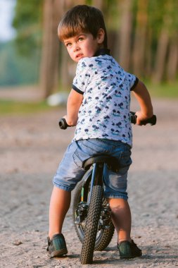 Dengeli bisikletteki şirin çocuk. Bisikletli çocuk. Anaokulu öğrencisi bisiklette denge kurmayı öğreniyor. Çocuklar için spor. Arka plan