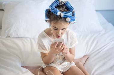 küçük kız curlers ve Smartphone ile poz