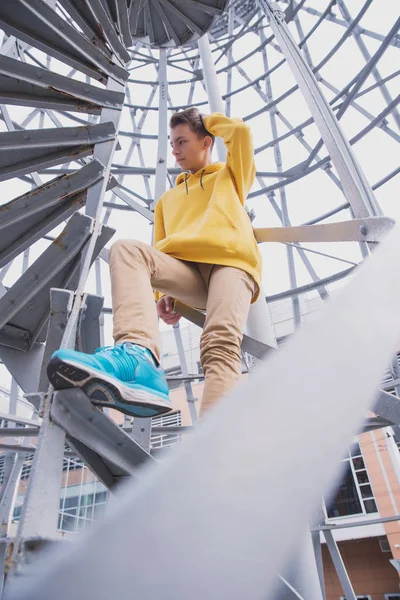 Een Jongeman Met Een Gele Capuchon Turquoise Sneakers Staat Een — Stockfoto