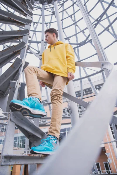 Een Jongeman Met Een Gele Capuchon Turquoise Sneakers Staat Een — Stockfoto