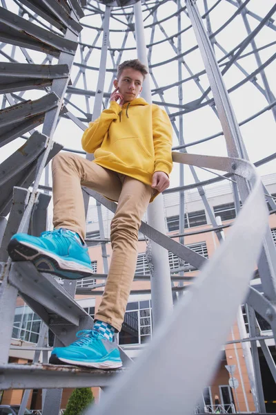 Een Jongeman Met Een Gele Capuchon Turquoise Sneakers Staat Een — Stockfoto