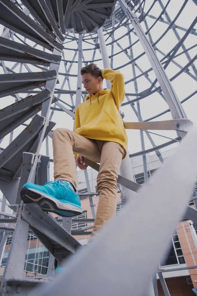 Een Jongeman Met Een Gele Capuchon Turquoise Sneakers Staat Een — Stockfoto