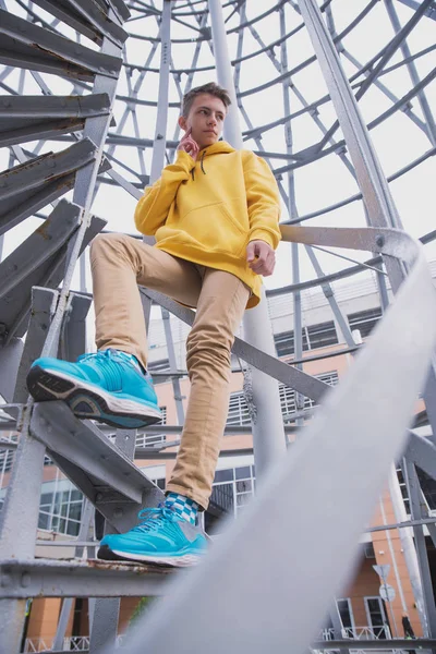 Een Jongeman Met Een Gele Capuchon Turquoise Sneakers Staat Een — Stockfoto