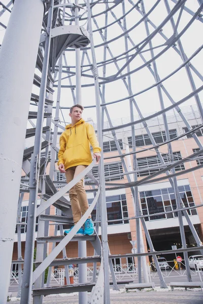 Een Jongeman Met Een Gele Capuchon Turquoise Sneakers Staat Een — Stockfoto