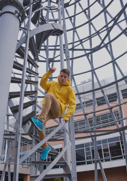 Een Jongeman Met Een Gele Capuchon Turquoise Sneakers Staat Een — Stockfoto