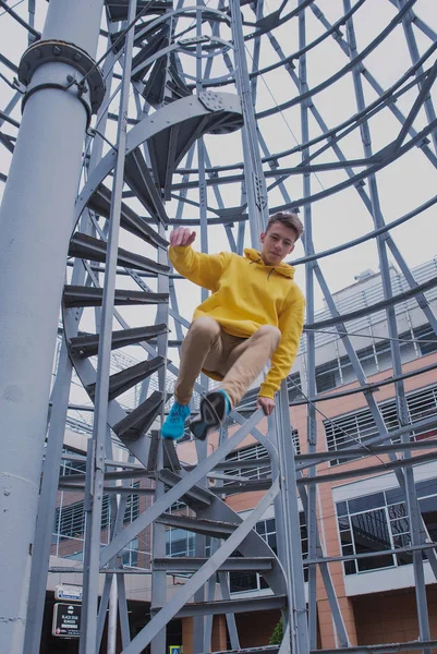 Een Jongeman Met Een Gele Capuchon Turquoise Sneakers Staat Een — Stockfoto