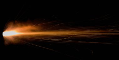 Siyah bir arka planda ateşli bir silahtan ateşlenen, uçan kıvılcımlar saçan, borudan fışkıran alevler...