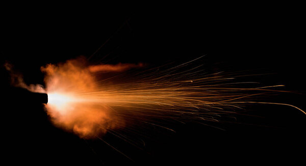 A shot from a firearm on a black background, a fiery exhaust with flying sparks, flames bursting out of the pipe