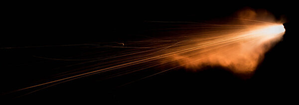 A shot from a firearm on a black background, a fiery exhaust with flying sparks, flames bursting out of the pipe. Fire comes out of the nozzle of a jet engine