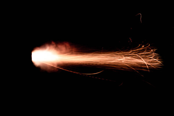 A shot from a firearm on a black background, a fiery exhaust with flying sparks, flames bursting out of the pipe. Fire comes out of the nozzle of a jet engine