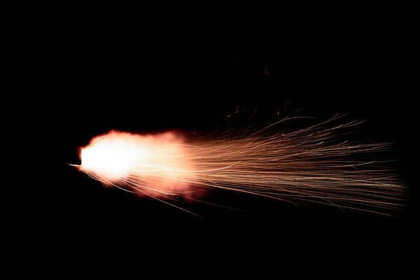 A shot from a firearm on a black background, a fiery exhaust with flying sparks, flames bursting out of the pipe. Fire comes out of the nozzle of a jet engine