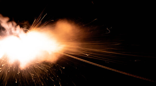 A shot from a firearm on a black background, a fiery exhaust with flying sparks, flames bursting out of the pipe. Fire comes out of the nozzle of a jet engine