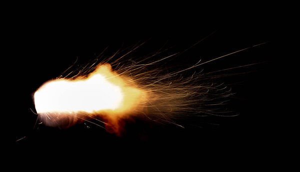 A shot from a firearm on a black background, a fiery exhaust with flying sparks, flames bursting out of the pipe. Fire comes out of the nozzle of a jet engine