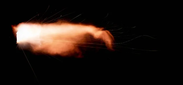 A shot from a firearm on a black background, a fiery exhaust with flying sparks, flames bursting out of the pipe. Fire comes out of the nozzle of a jet engine