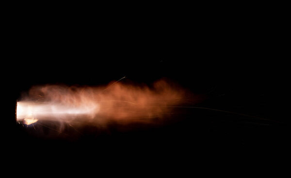 A shot from a firearm on a black background, a fiery exhaust with flying sparks, flames bursting out of the pipe. Fire comes out of the nozzle of a jet engine