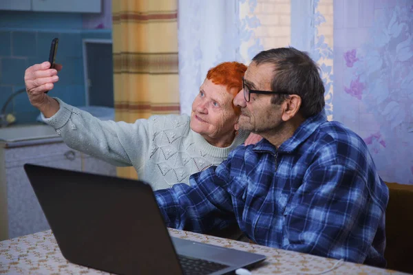 Elderly people work with a laptop, grandparents master mobile communication and Internet technologies, and elderly people use gadgets to communicate with their loved ones in conditions of self-isolation