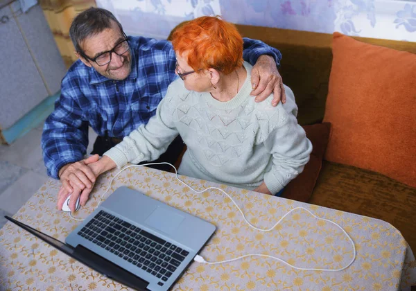 Elderly people work with a laptop, grandparents master mobile communication and Internet technologies, and elderly people use gadgets to communicate with their loved ones in conditions of self-isolation