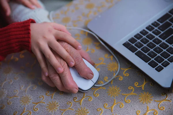 A granddaughter teaches her grandmother to work on a computer, a little girl plays on a laptop with an elderly woman, taking care of the elderly in the study of Internet technologies