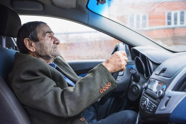An elderly man driving a car, a grandfather driving a car, a solid man driving around the city
