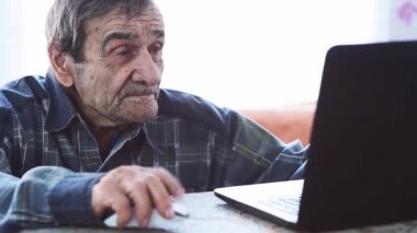 Dizüstü bilgisayarda yaşlı bir adam. Büyükbaba evde kalıyor ve sosyal ağlar aracılığıyla ailesi ve arkadaşlarıyla iletişim kuruyor. Salgın sırasında emeklilerin evlerinin geri çekilmesi.