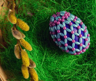 Yeşil ve ahşap arka planda boncuklu Paskalya yumurtaları. Paskalya bayramının sembolü boncuklarla kaplıdır. Sepetteki parlak Paskalya yumurtaları