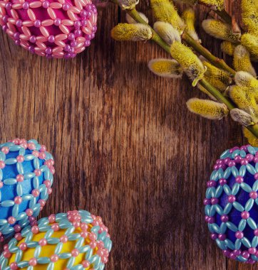 Yeşil ve ahşap arka planda boncuklu Paskalya yumurtaları. Paskalya bayramının sembolü boncuklarla kaplıdır. Sepetteki parlak Paskalya yumurtaları