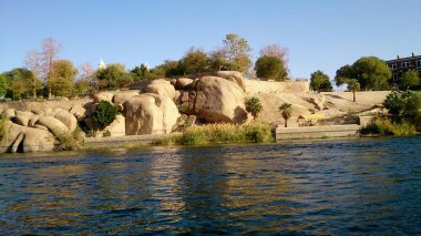 Nil Nehri 'nin kıyısındaki büyük kayalarla desteklenen görüş noktası. Bu yerin tipik koltuk ve ağaçlarını görebilirsiniz..