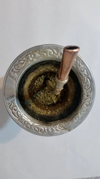 Top view of a pumpkin where the drink called mate with metal rim is made. In this infusion you can see part of the pumpkin (container), yerba mate, a straw called \
