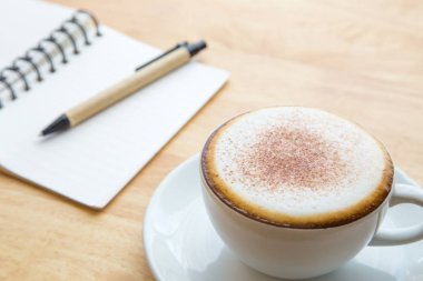 Açık defter ile kahve fincanı.