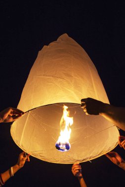 Hands praying while releasing paper Yee-Peng flying lantern in K clipart