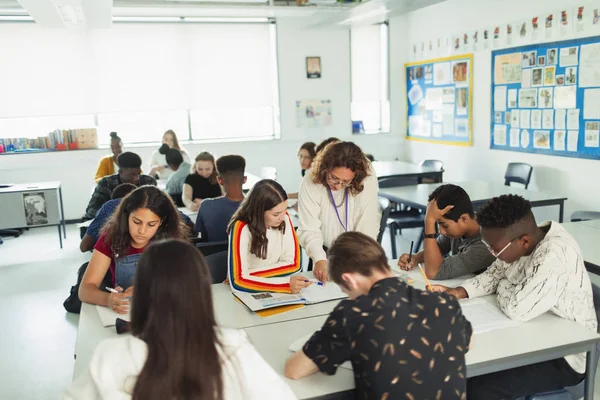 教室で勉強する生徒を助ける高校教師 — ストック写真
