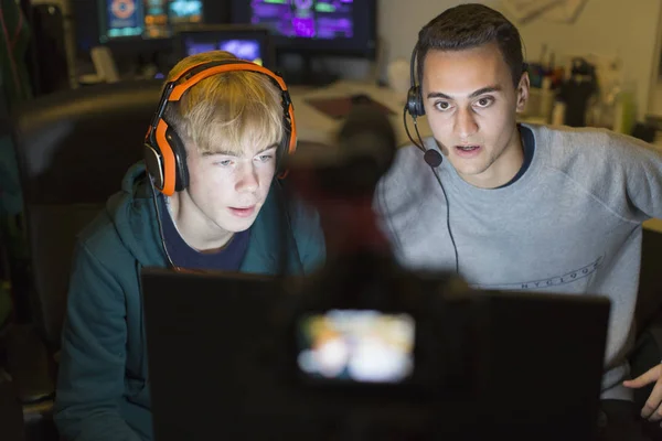 若いです男の子とともにヘッドフォン再生ビデオゲームでコンピュータで暗い部屋 — ストック写真