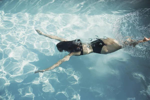 穿着比基尼的女人在阳光灿烂的游泳池里游泳 — 图库照片