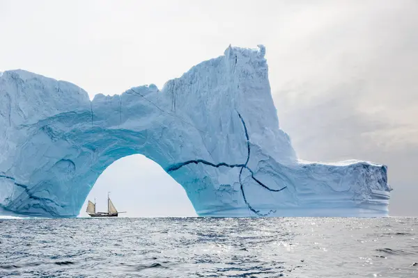 在格陵兰岛大西洋上宏伟的冰山拱后航行的船只 — 图库照片