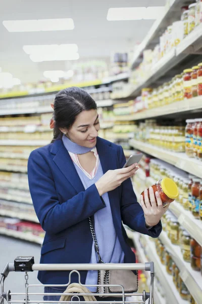 Frau Mit Smartphone Scannt Etikett Auf Glas Supermarkt — Stockfoto