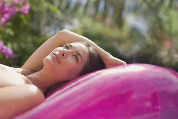 Heitere Frau entspannt sich auf rosa aufblasbarem Pool-Floß — Stockfoto