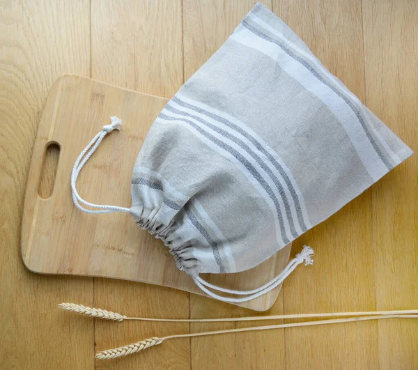 Многоразовый льняной мешок для хлеба на деревянной разделочной доске — стоковое фото