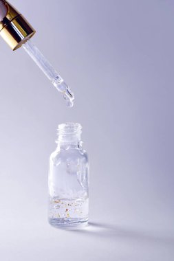 Altın parçacıkları damlatıcıyla parlayan serum şişesi