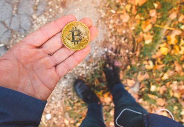 Tutan bir altın bitcoin, bacaklar ve b arka plan bulanık el