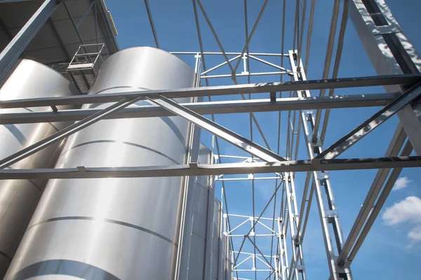 Modern storage technology agro-industry, metal containers for grain business  granary trail perspective . Grain drying Complex, Commercial  Seed Silos in Summer , sunny day, blue sky, white clouds .