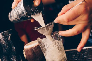 Barmen, barın tezgahına süzgeç gibi beyaz kokteyl döker. Profesyonel bakış açısı. Moda tarzı alkollü içecek. Gece kulübünde tasarımcılar ve konsept servisi barmeni.