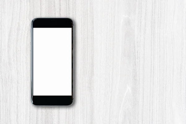Smartphone berbaring datar dengan layar putih kosong dan ruang fotokopi pada latar belakang kayu — Stok Foto