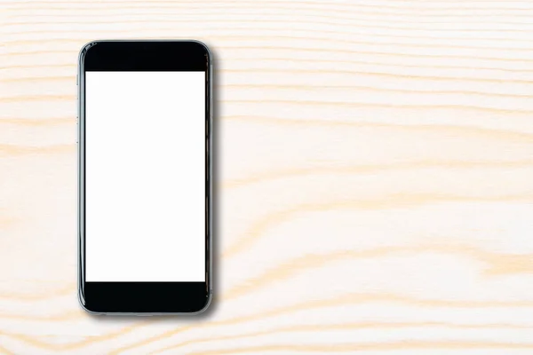 Smartphone berbaring datar dengan layar putih kosong dan ruang fotokopi di atas meja kayu — Stok Foto