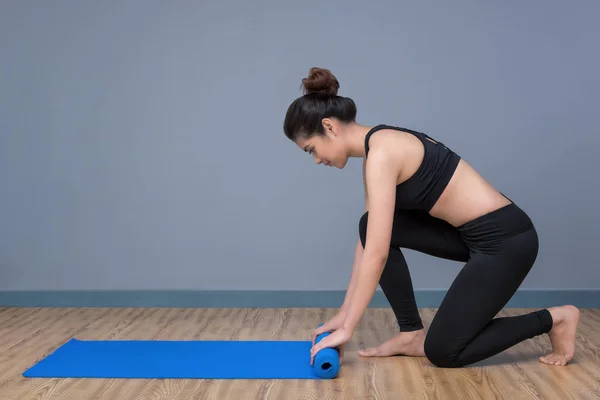 Giovane donna asiatica preparare tappetino yoga per praticare yoga a yoga sana palestra sportiva. Yoga e meditazione hanno buoni benefici per la salute. Concetto fotografico per Yoga Sport e stile di vita sano . — Foto Stock