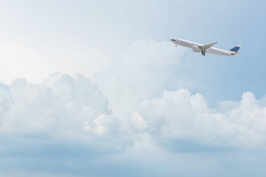 Ticari uçak uçan parlak mavi gökyüzü ve beyaz bulutlar üzerinde