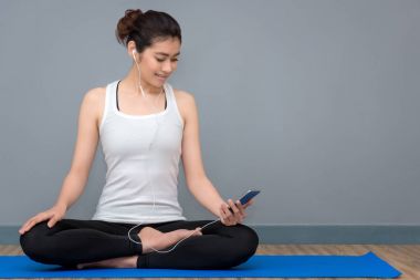 Genç Asyalı kadın önce pratik yoga müzik keyfini çıkarın