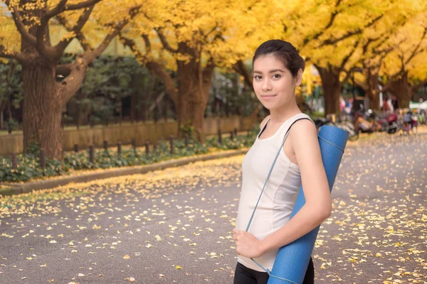 Onun yoga mat açık Parkı'nda tutan genç Asyalı kadın. — Stok fotoğraf